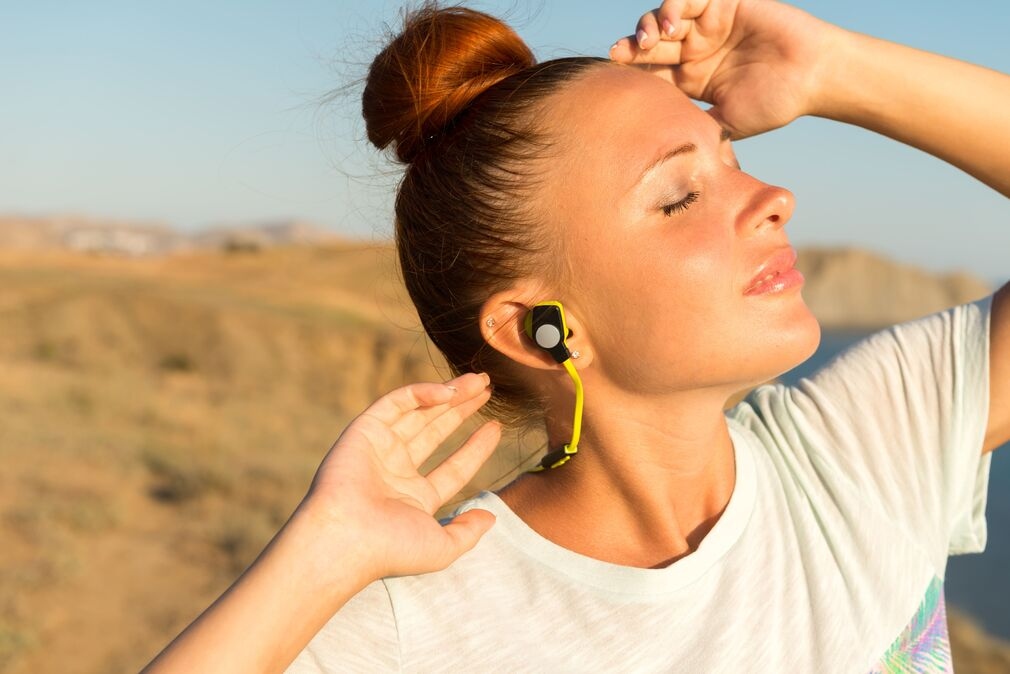 In-Ear Kopfhoerer mit Smartphone im mobilen Arbeitsalltag